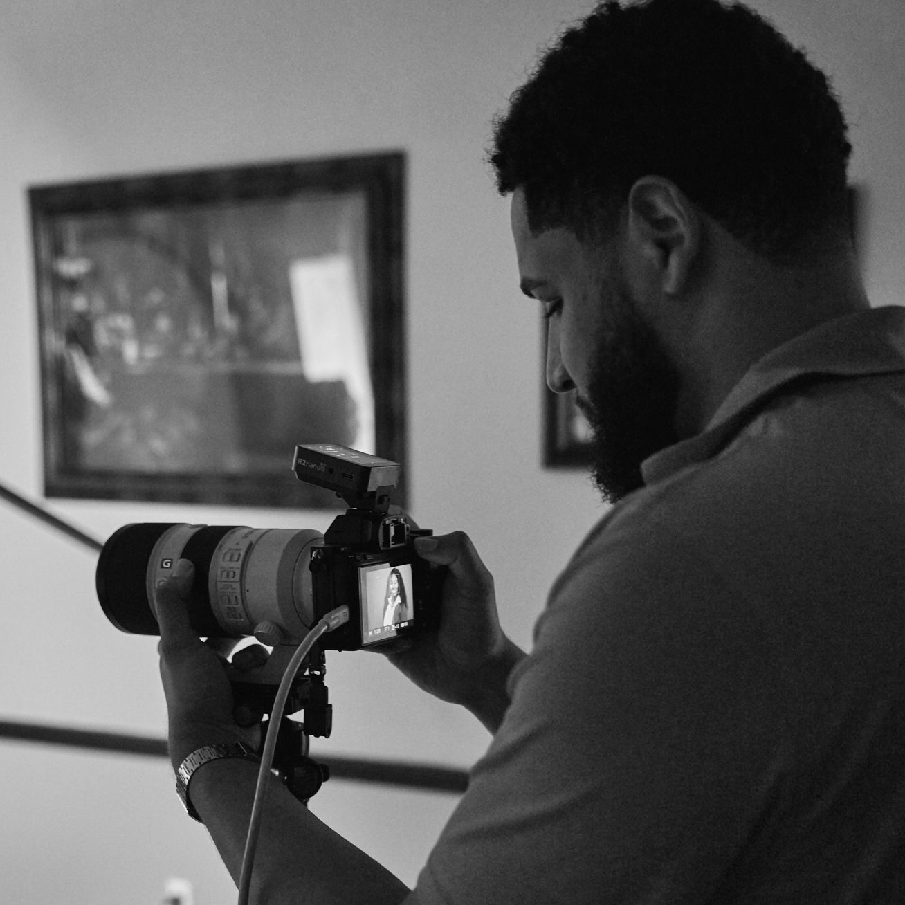 Black and white photo of Gerson checking a shot on a tethered camera