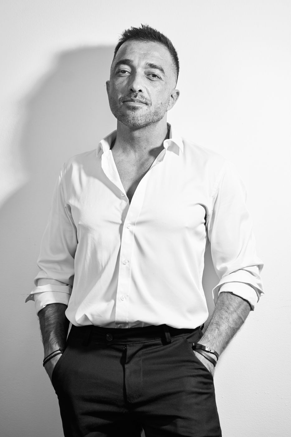Black and white portrait of a man in a white shirt leaning on a wall