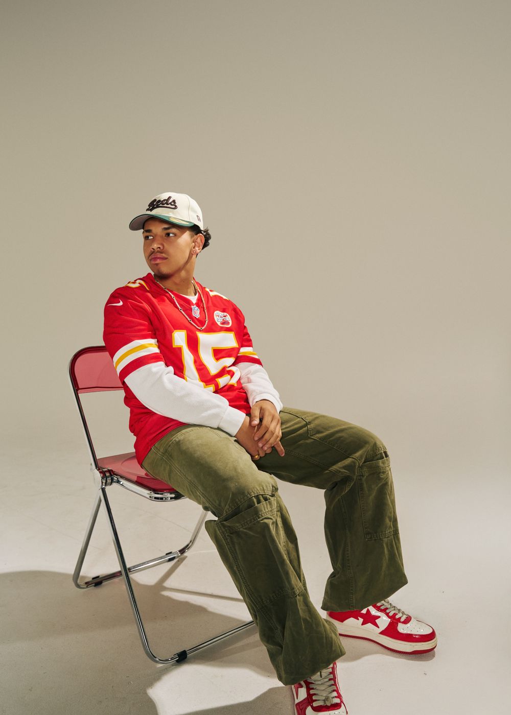Man in a red football jersey and cap seated on a folding chair
