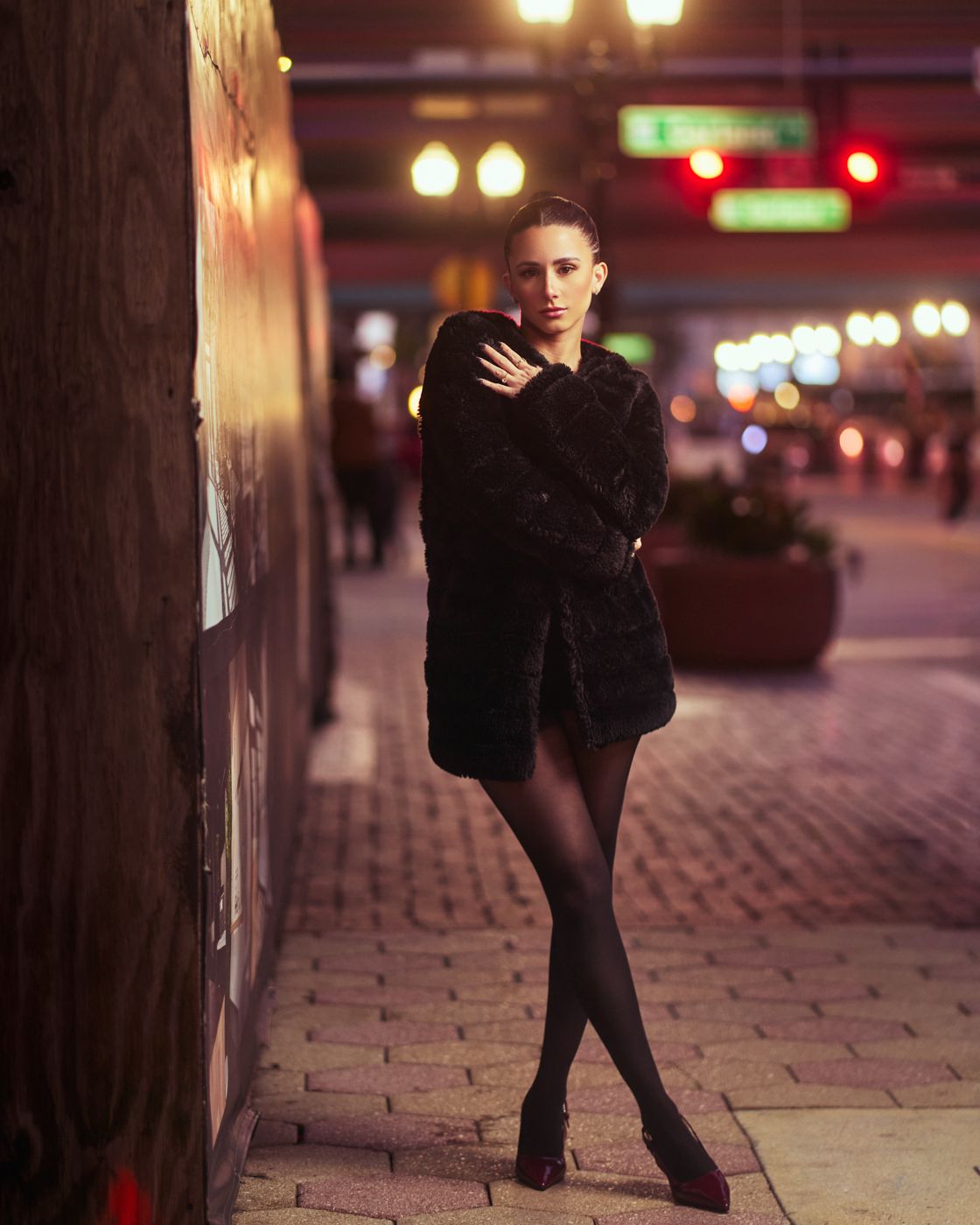 Woman in a black coat on a lit downtown Orlando street at night