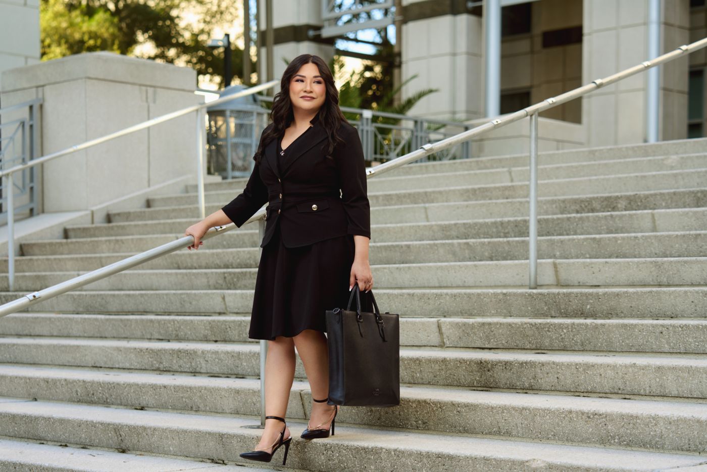 Woman in a black suit walking down downtown steps with a leather tote