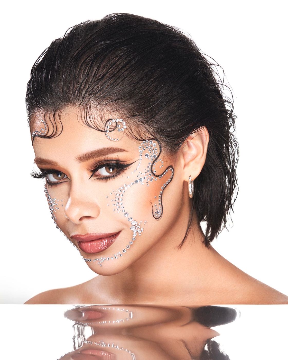 Beauty portrait with silver face jewels and a reflective surface
