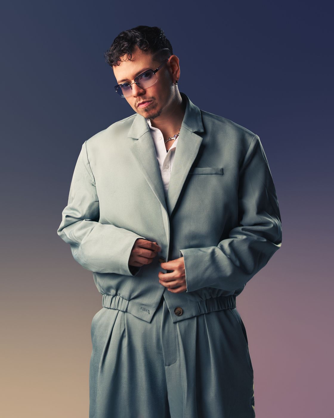 Model in an oversized sage suit against a purple gradient