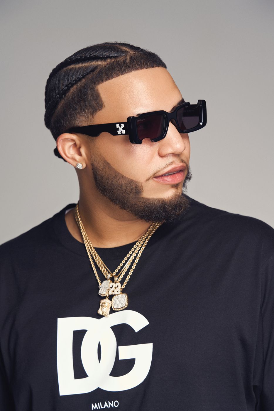 Artist in sunglasses and a gold chain against grey