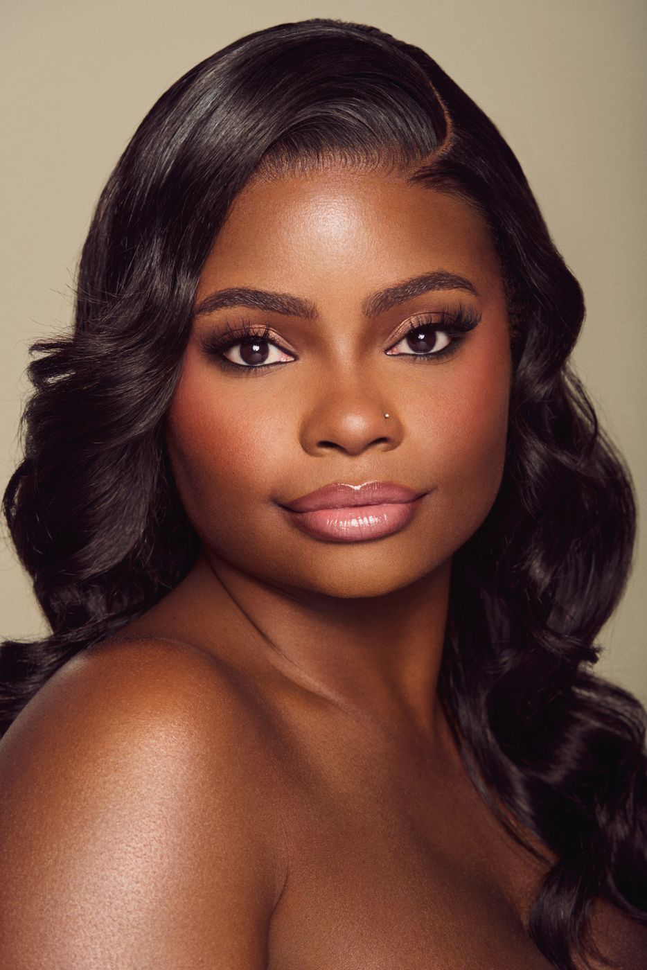 Glam beauty portrait with soft curls on a warm backdrop