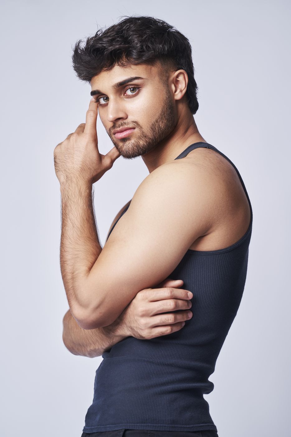 Model in a black tank top with hand at his face
