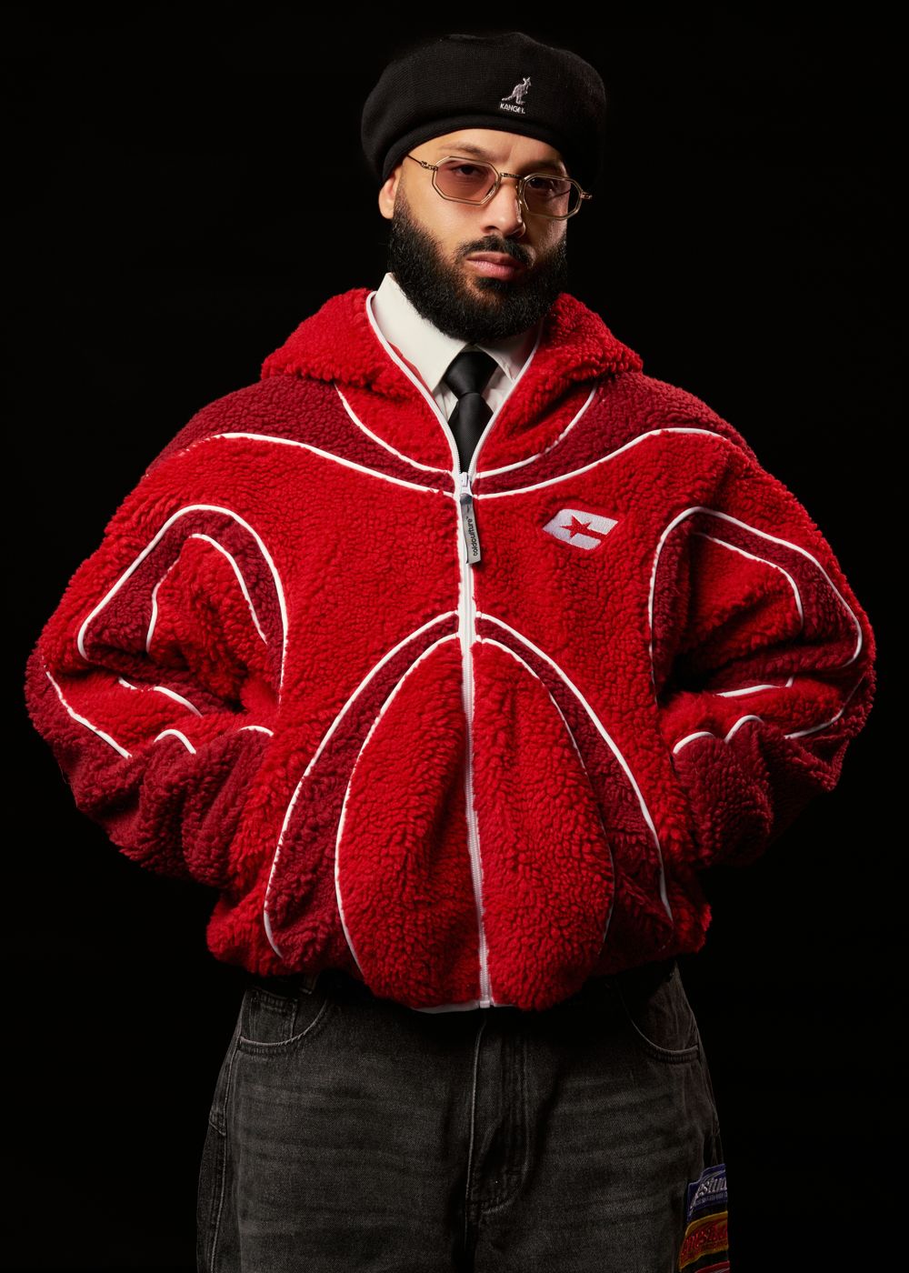 Alex Rose in a red sherpa jacket and beret against black