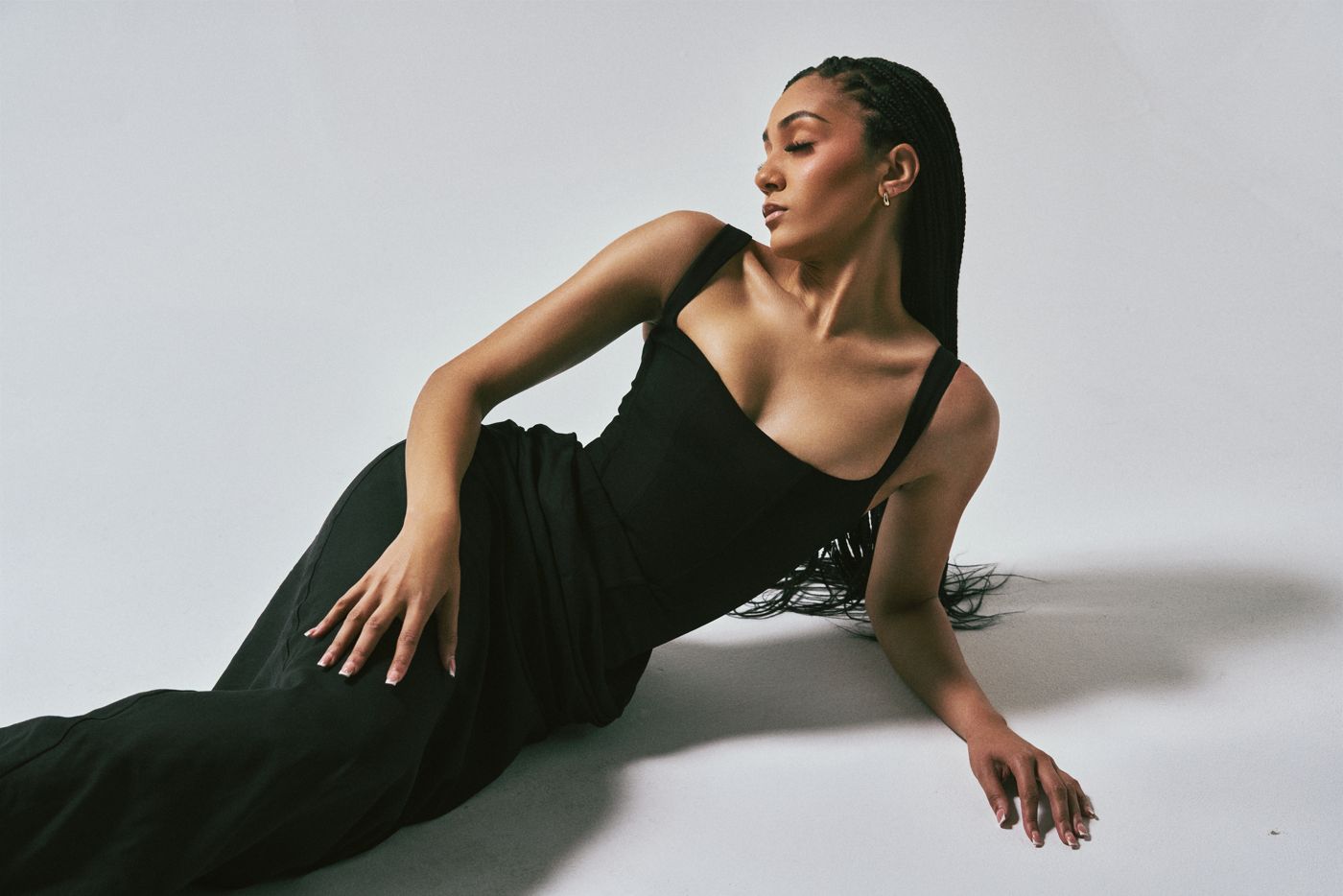 Model in a black gown reclining on a white studio floor