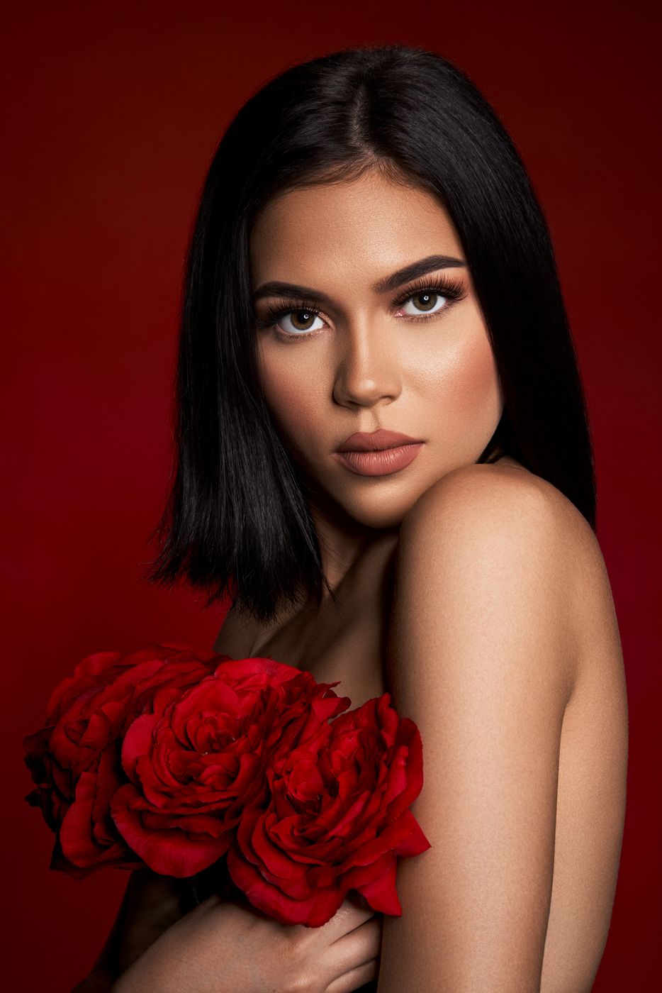 Woman holding red roses against a deep red backdrop