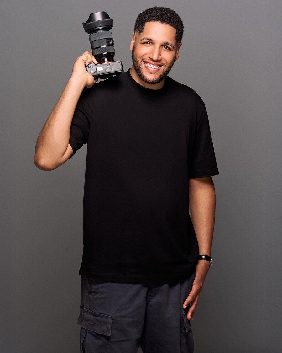 Gerson Lopez holding a camera on his shoulder, smiling