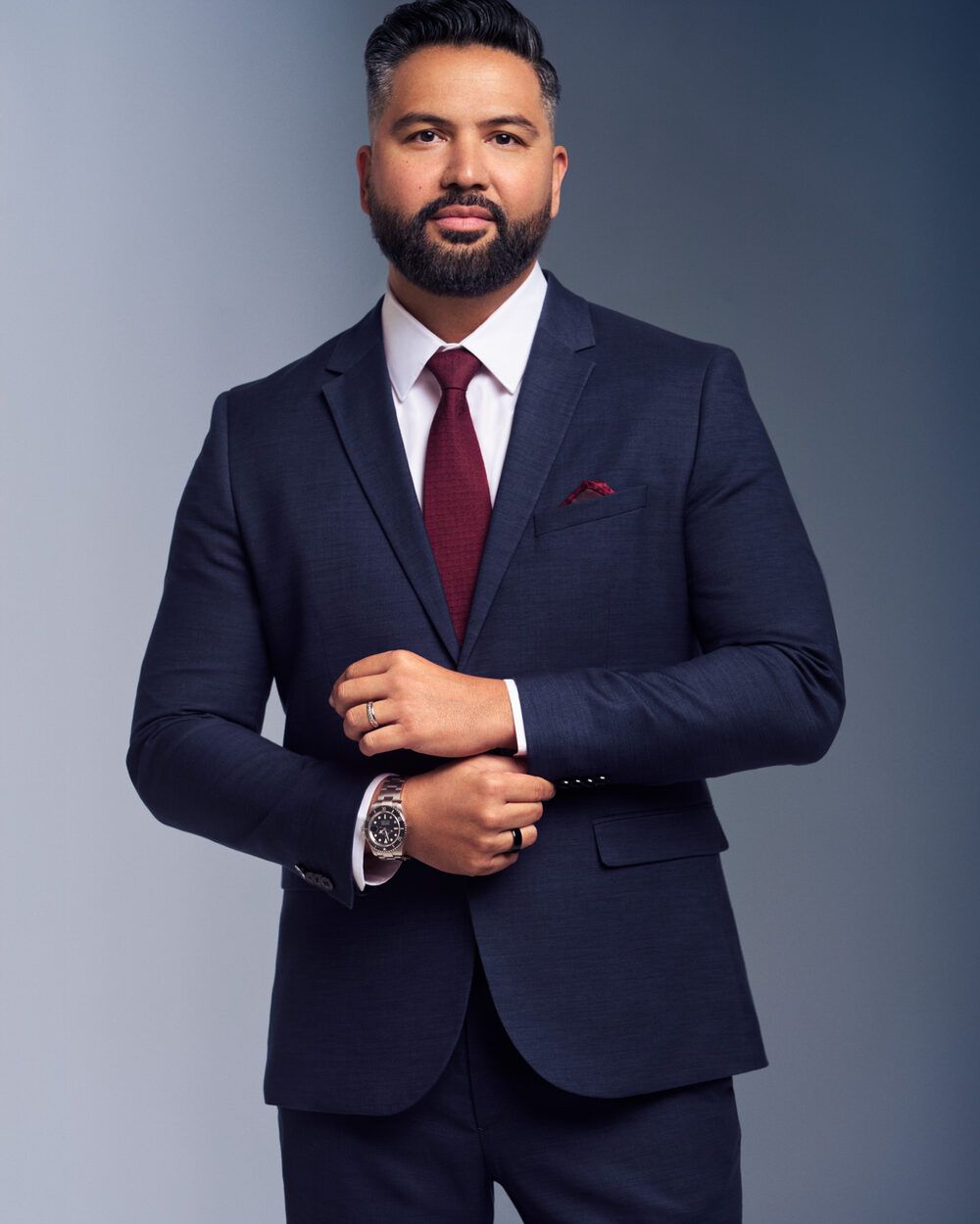 Executive in a navy suit and burgundy tie with hands together