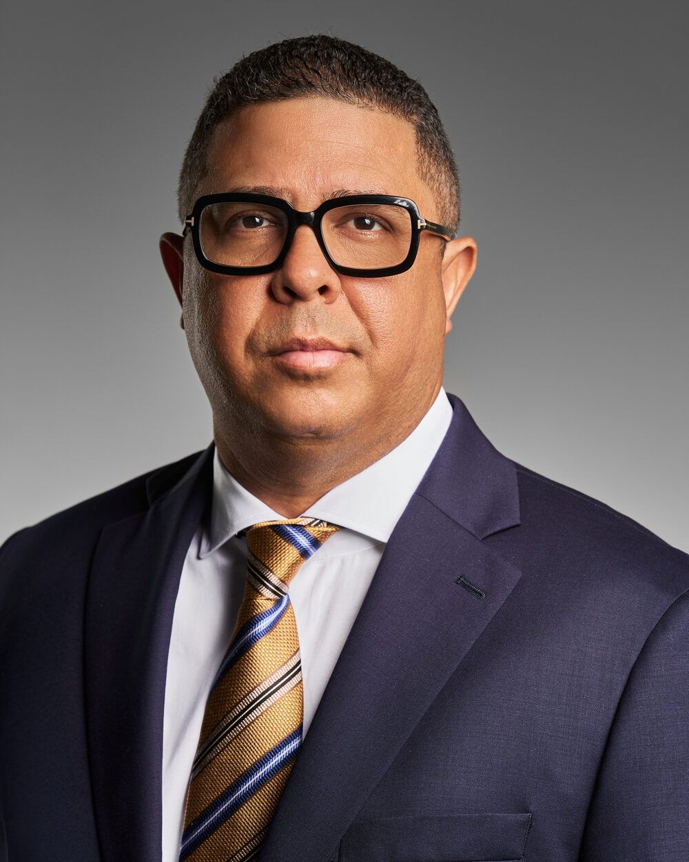Executive in glasses, navy suit and gold striped tie