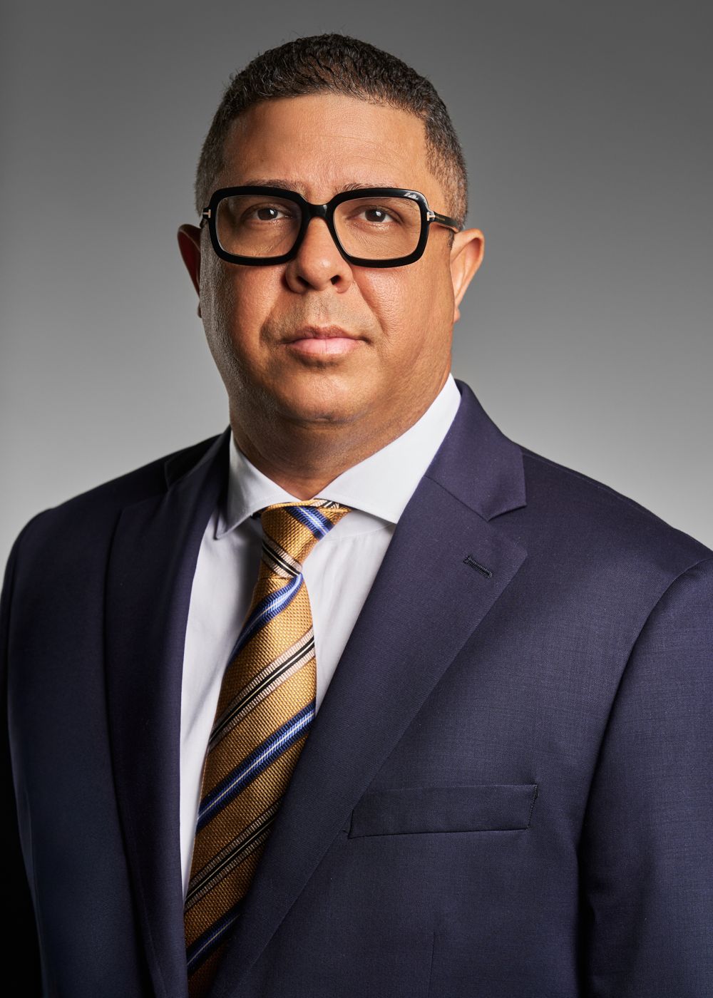 Man in glasses, navy suit and striped tie