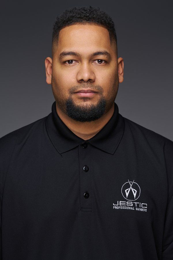 Barber in a black Jestic polo against a charcoal backdrop