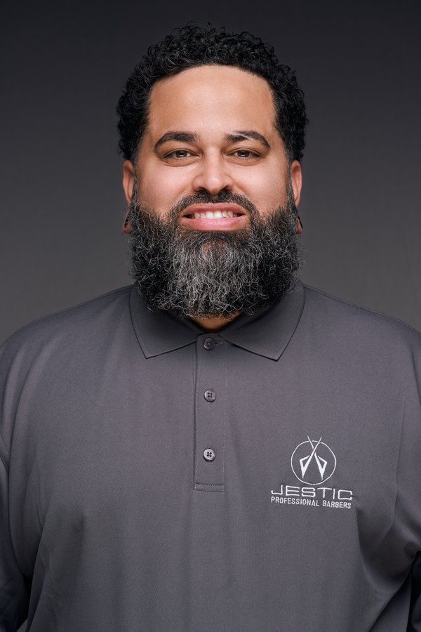Smiling barber with a full beard in a grey Jestic polo